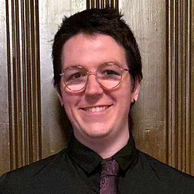 Cammi Broadbent Headshot. They are smiling in professional attire.